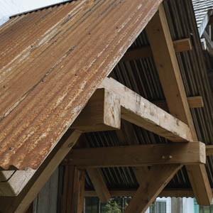 Close-up of a rustic timber framed structure with a weathered corrugated rusty metal roof