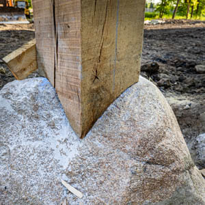 A White Oak timber post expertly scribed to the irregular surface of a natural rock foundation footing.