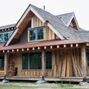 A large timber frame porch made from White Oak with a rusty corrugated metal roof and a cedar shingle gable.